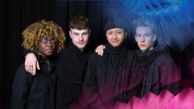 Four students standing together and looking into the camera wearing black garments designs by a student.
